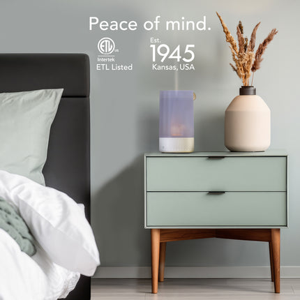 Bedroom scene with a nightstand, diffuser, and vase against a gray wall with ETL Listed branding.