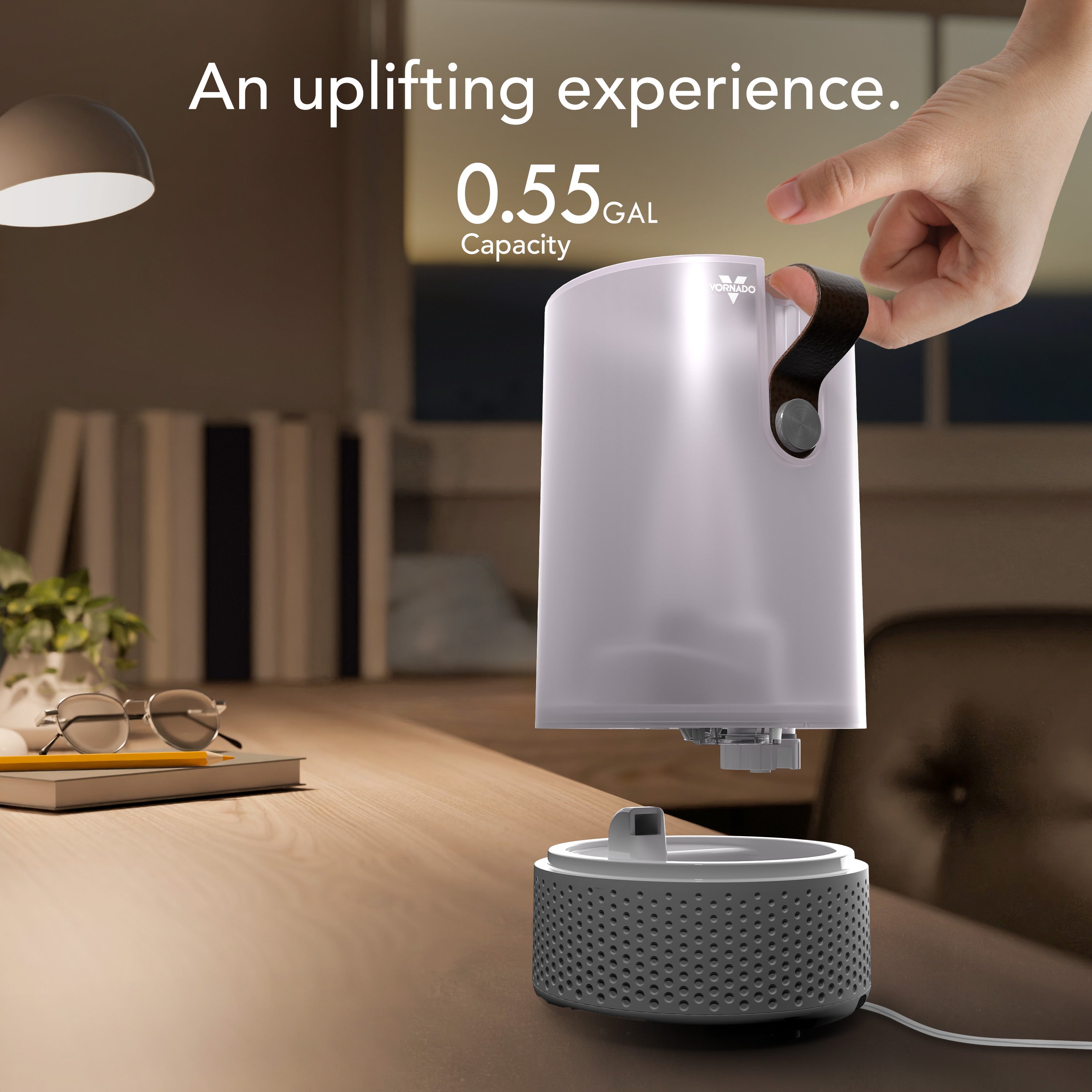 Humidifier on a table with a hand holding the top, in a room setting.