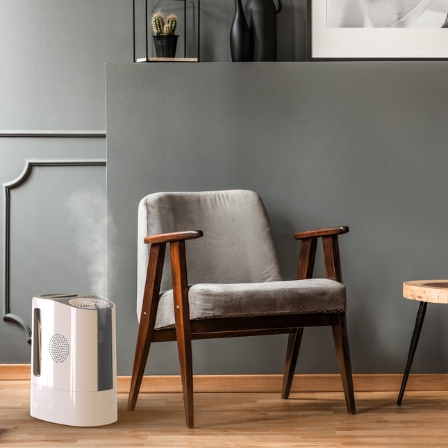 Gray armchair with wooden arms and legs in a room with a gray wall and small table.