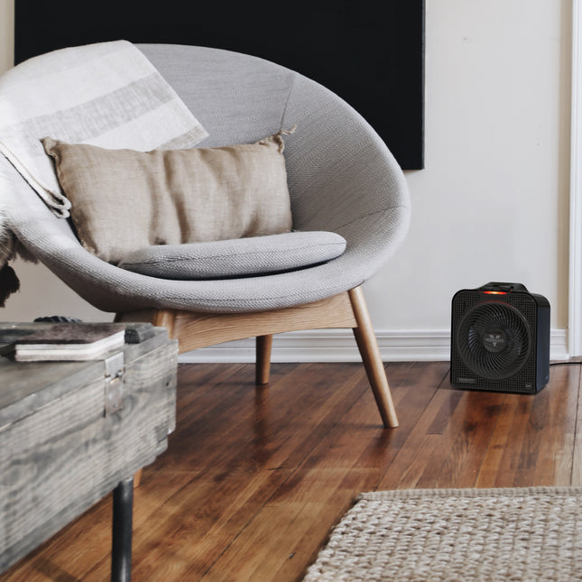Modern chair with a pillow and space heater on a wooden floor.