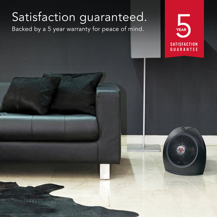 Black leather sofa in a living room with a black portable heater, featuring a 5-year satisfaction guarantee.