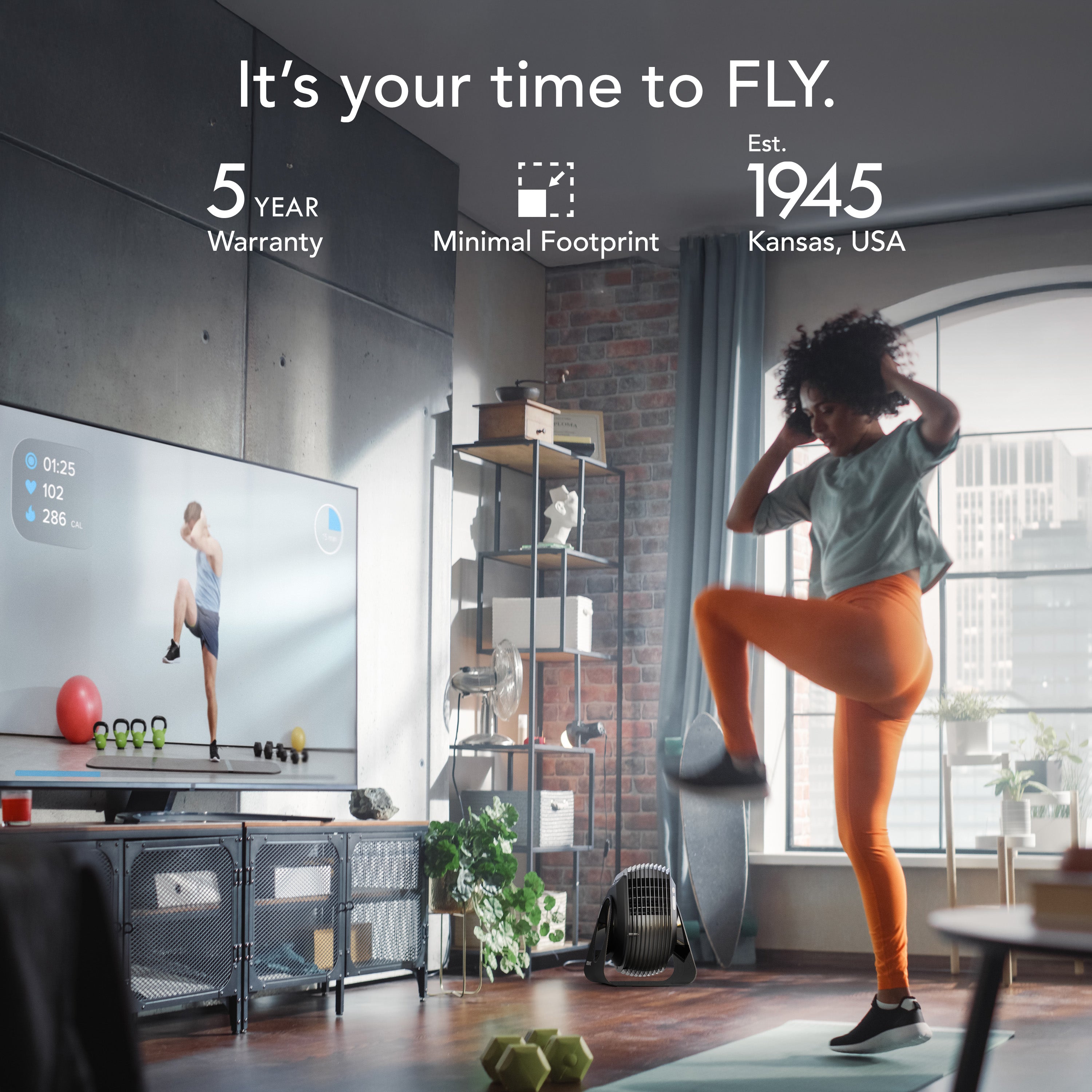 Person exercising on a mat in a modern living room with a TV displaying a workout.