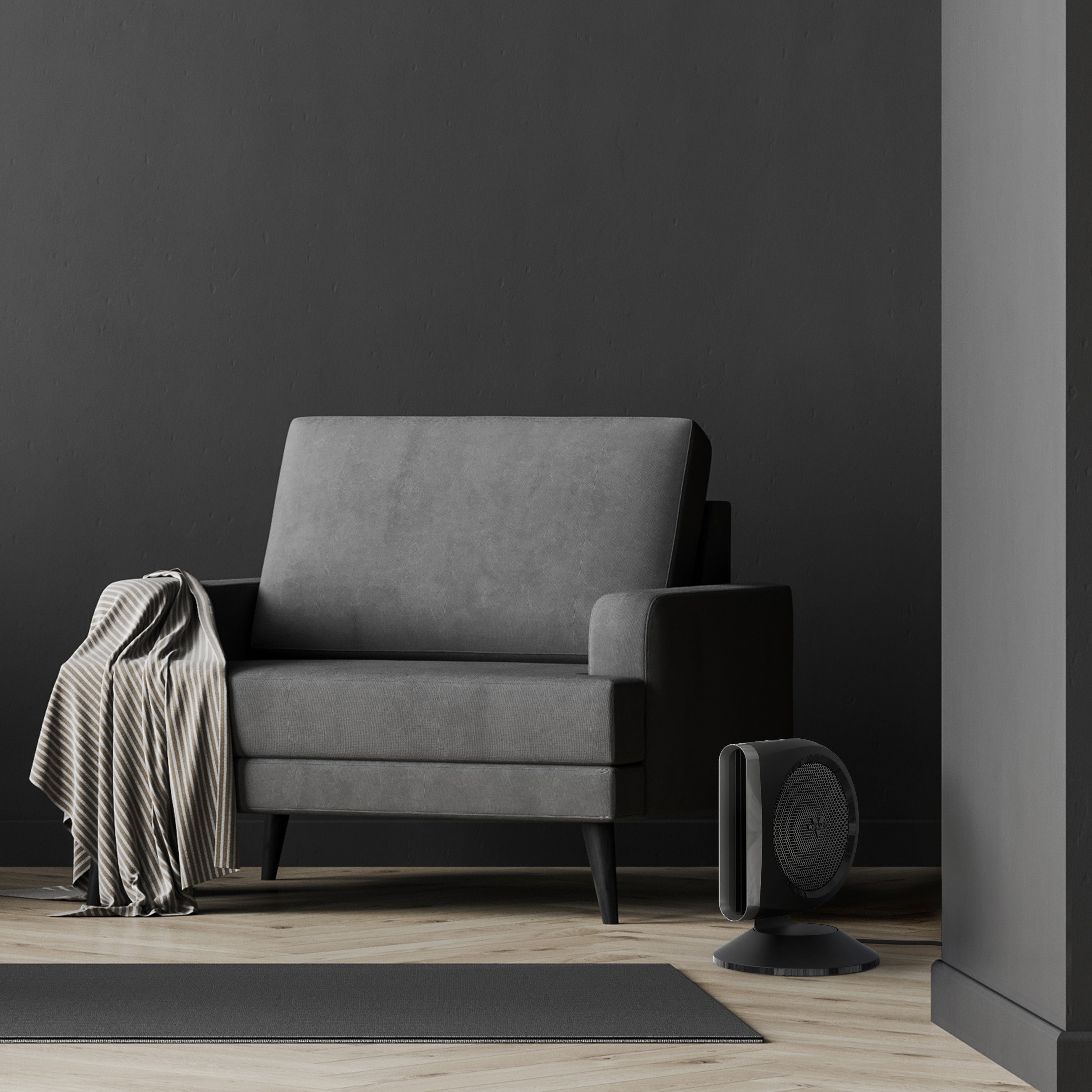 Gray armchair with a blanket and a small fan against a dark wall.
