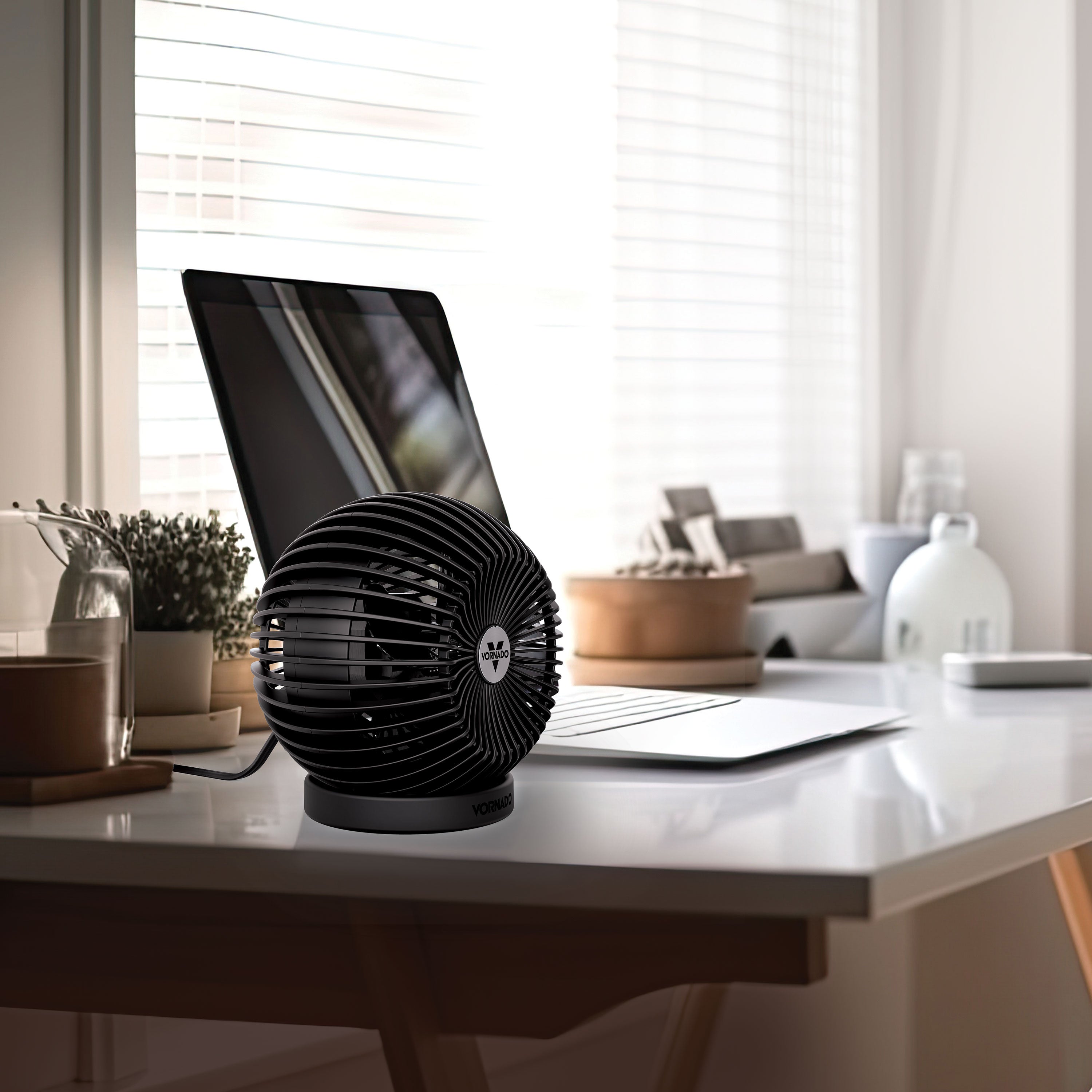 Black desk fan on a desk with a laptop in a home office setting
