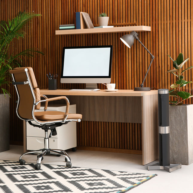 Modern office desk with computer, chair, and decorative elements in a home office setting.
