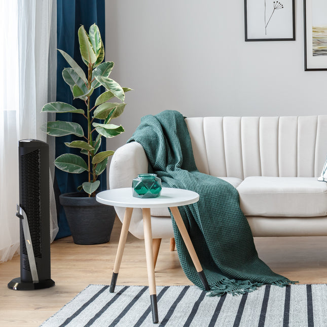 Modern living room with a white sofa, green blanket, and a floor-standing air purifier.