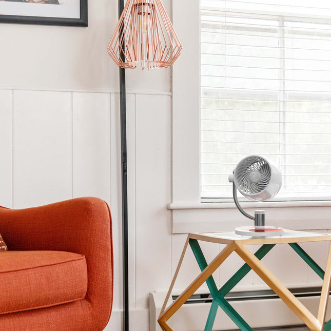 Modern living room with orange armchair, geometric table, and decorative lamp.