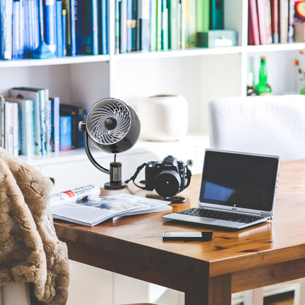 Wooden desk with laptop, camera, and books in a home office setting