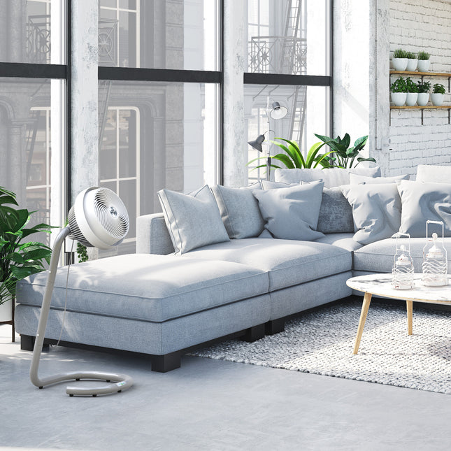 Modern living room with a light gray sectional sofa, floor fan, and coffee table.