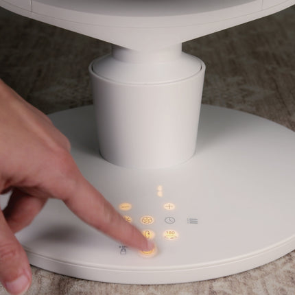 Hand pressing a button on a white electronic device with illuminated buttons.