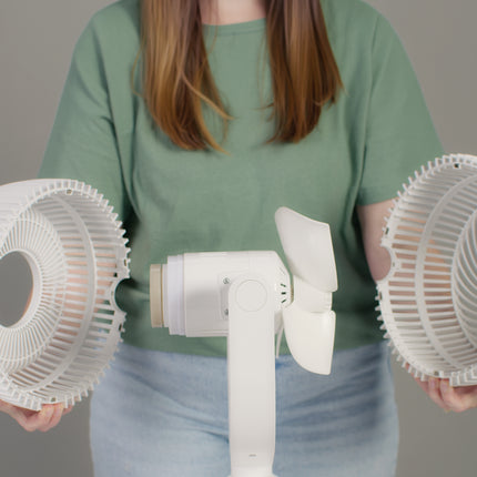 Person holding a white handheld fan with two circular pieces on a plain background