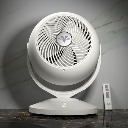 White Vornado fan on a marble surface with a remote control in the background.