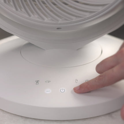 Person Pressing buttons on a white vornado fan.