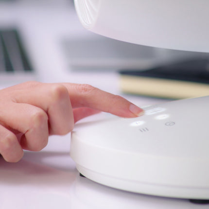 Hand pressing a button on a white electronic device with a blurred background