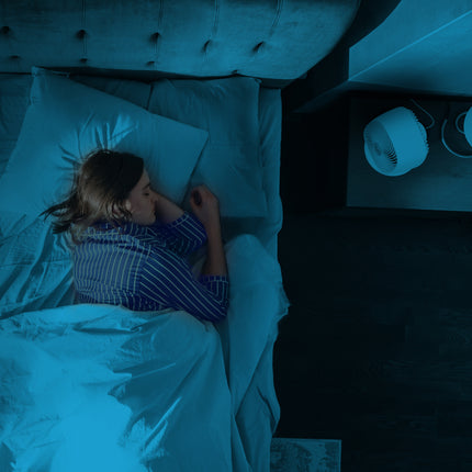 Person lying in bed under blue lighting, possibly using a smartphone.