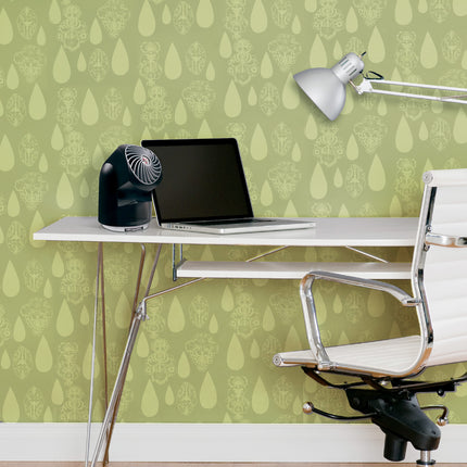 Modern office setup with a desk, chair, laptop, and fan against a green patterned wall.