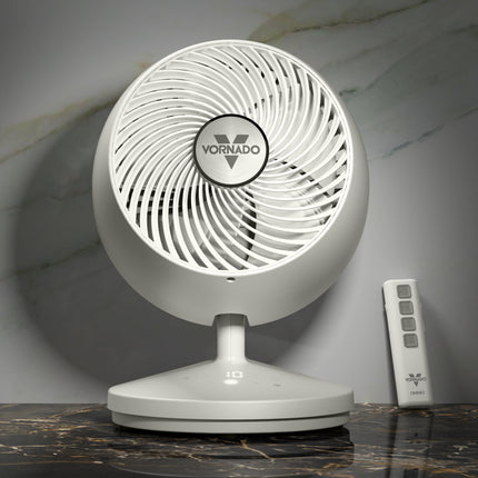 White Vornado fan on a marble surface with a remote control.
