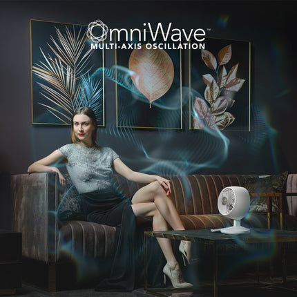 Woman sitting on a couch with a fan in front of a wall with 'omniWave' branding.