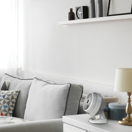 Black fan on a side table next to a couch
