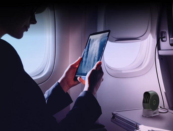 A woman using the Pebl Portable Fan on an airplane.