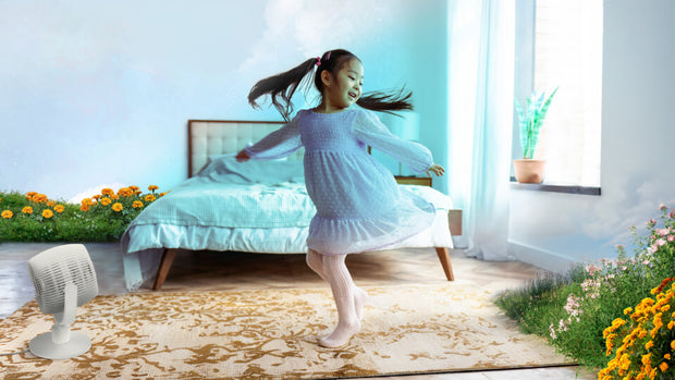 Little girl dancing in bedroom next to EOS 9. To the left of her, a blue sky is on the wall and wild flowers are on the floor to indicate breeze mode.