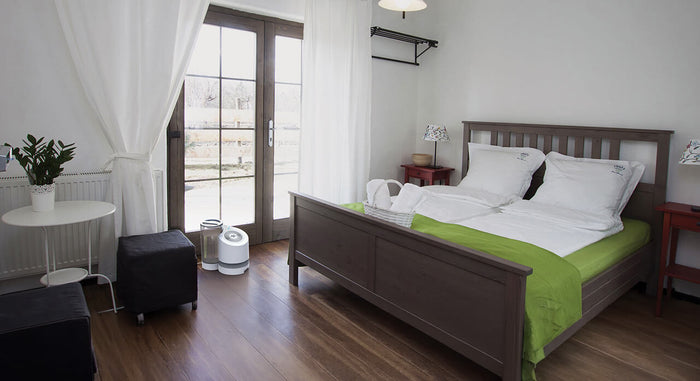 lifestyle of a ev100 evaporative humidifier in a bedroom by french doors 
