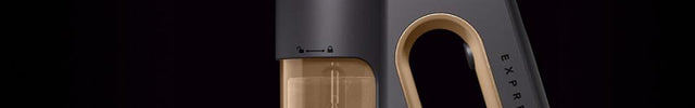 The express handheld garment steamer facing left against a dark background. There is steam coming out of the nozzle.