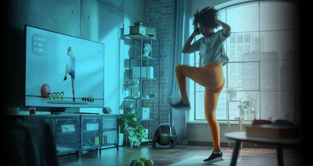 FLY MAX providing whole room circulation as a woman works out to an exercise program on her tv in her living room.