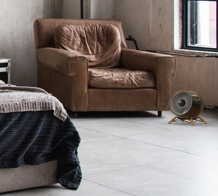 glide heat in a modern bedroom in front of a leather chair and facing a bed. Natural light fills the room from a window behind the heater.