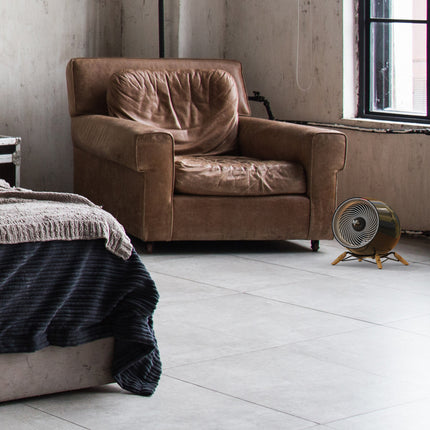 glide heat in a modern bedroom in front of a leather chair and facing a bed. Natural light fills the room from a window behind the heater.