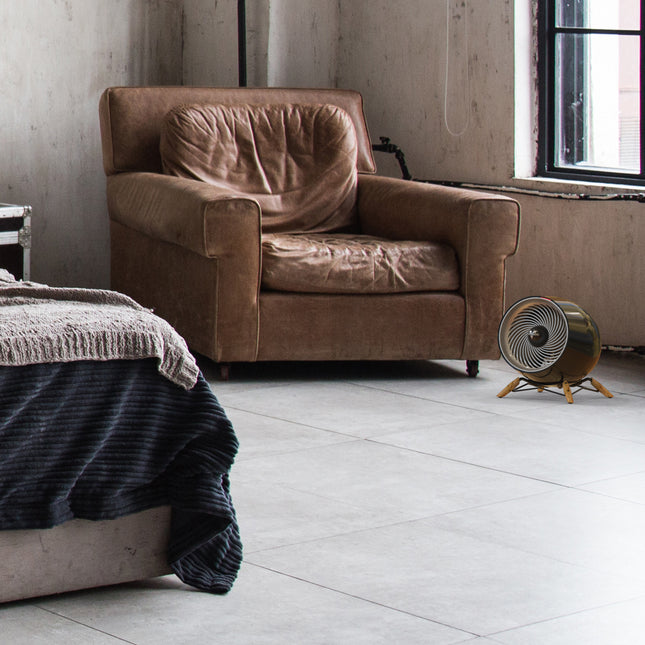 glide heat in a modern bedroom in front of a leather chair and facing a bed. Natural light fills the room from a window behind the heater.