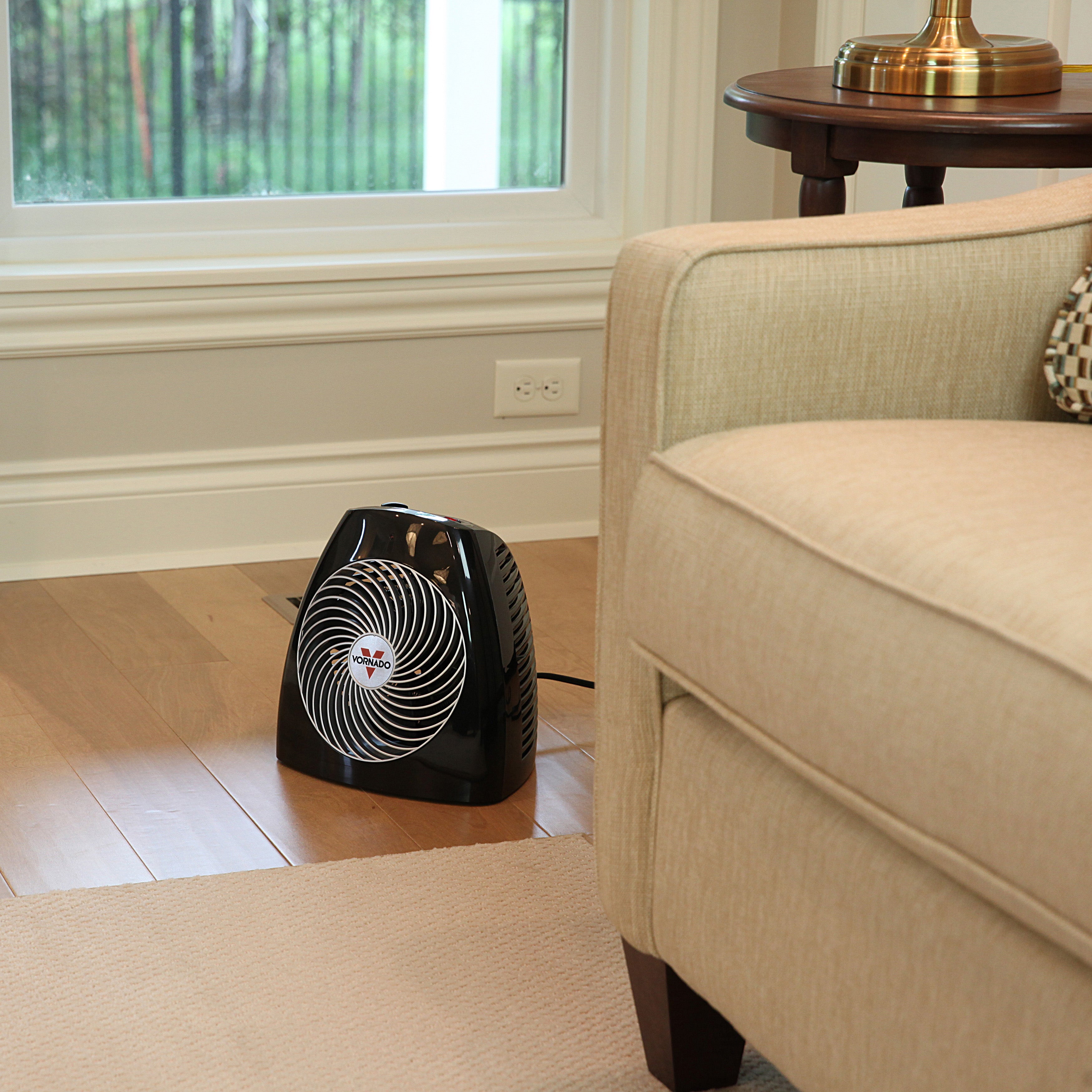 MVH in a living room next to a tan couch on hardwood floors with white designed baseboards and natural room lighting
