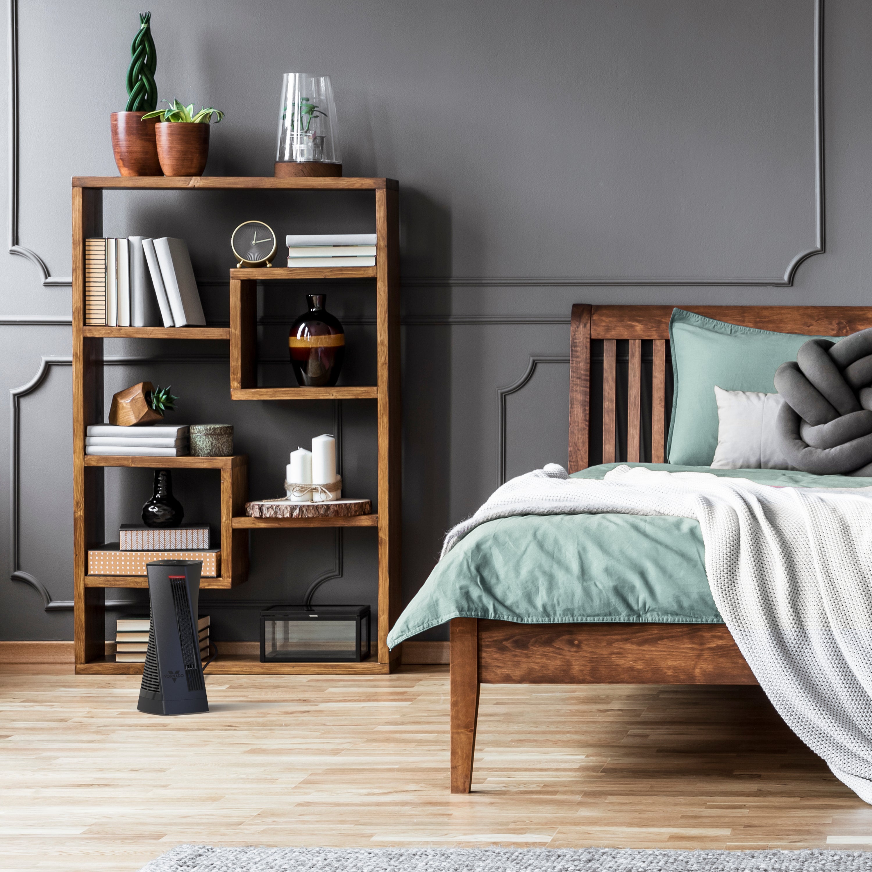 oscth1 in a bedroom on wood floors facing a wood-framed bed with room decor on a wooden shelf behind the heater