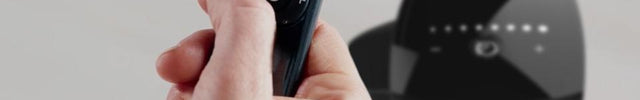 Close up of a hand holding a OZI42 Tower Circulator remote. blurred in the background is a OZI42 Tower Circulator.