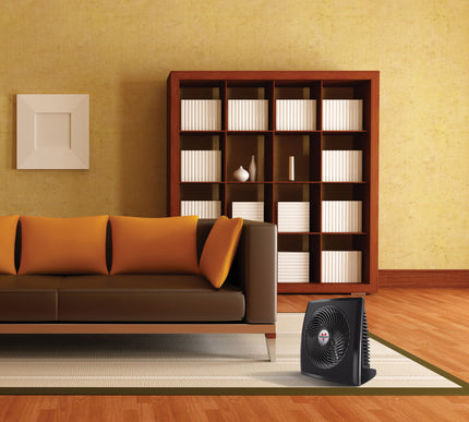 PVH heater on the floor in an orange tinted living area and next to a brown leather couch