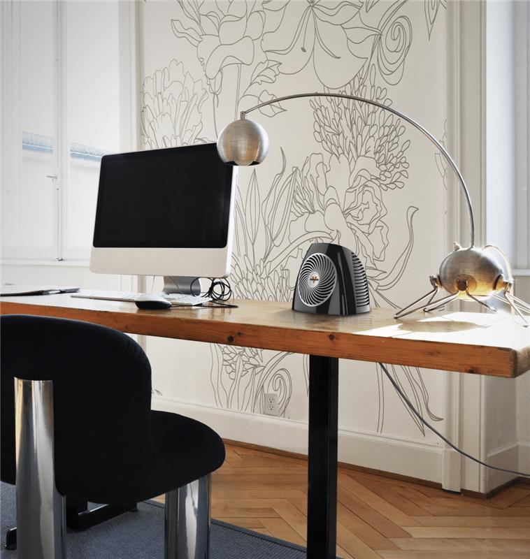 VH202 heater on a wooden desk with a white wallpaper backdrop and wood floors. Next to the heater is a white desktop computer setup and black office chair