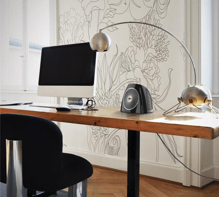 VH202 heater on a wooden desk with a white wallpaper backdrop and wood floors. Next to the heater is a white desktop computer setup and black office chair