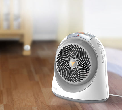 sensa heater on hardwood floors with a slightly visible crib and crib sensing remote behind the heater