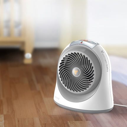 sensa heater on hardwood floors with a slightly visible crib and crib sensing remote behind the heater