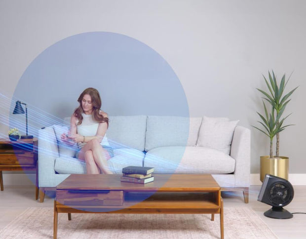 A woman is sitting on a couch with Strata to her far right. A transparent blue circle is overlayed on her to showcase spot cooling.
