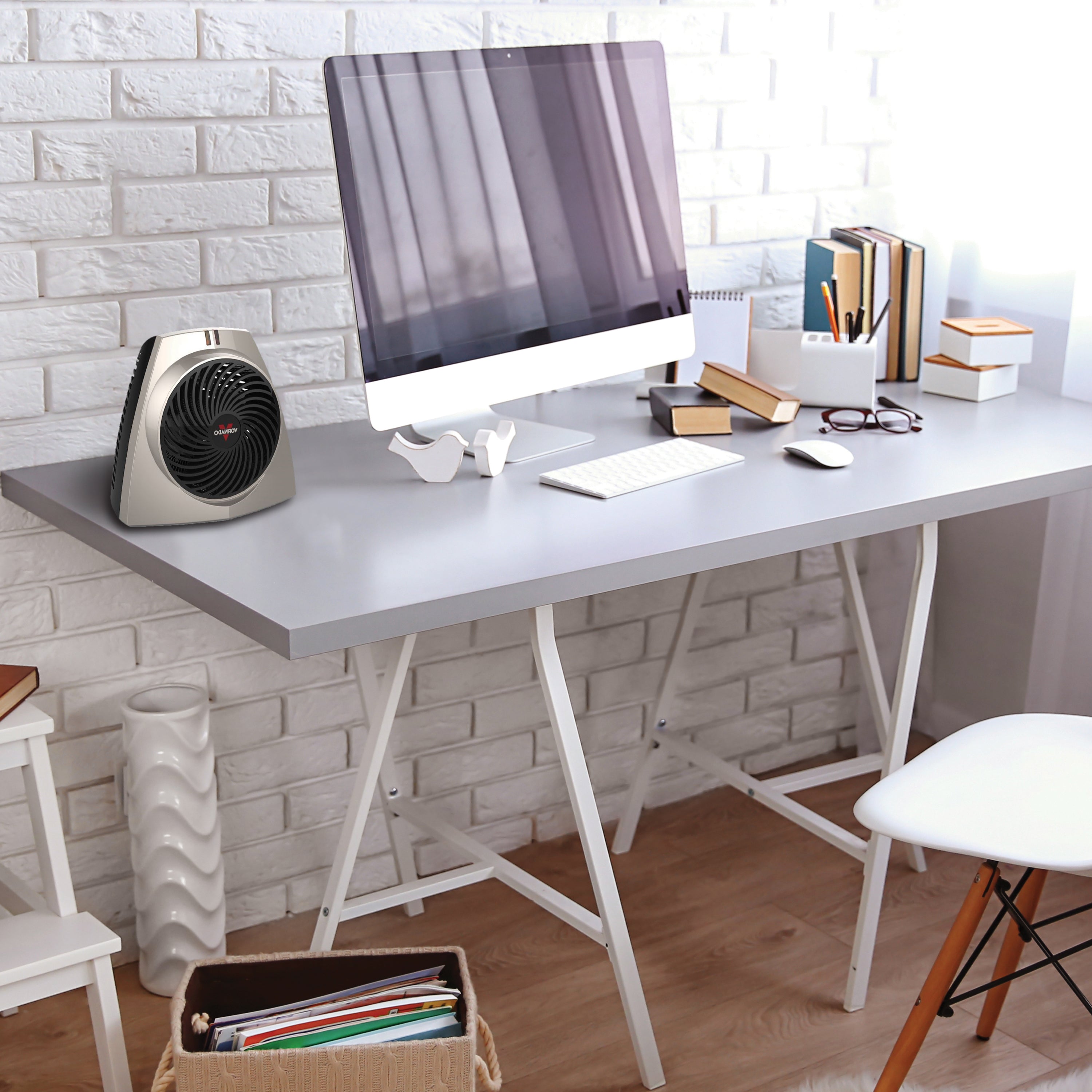 VH203 personal space heater on an office desk with a white brick wall backdrop and a computer setup with various books on the desk