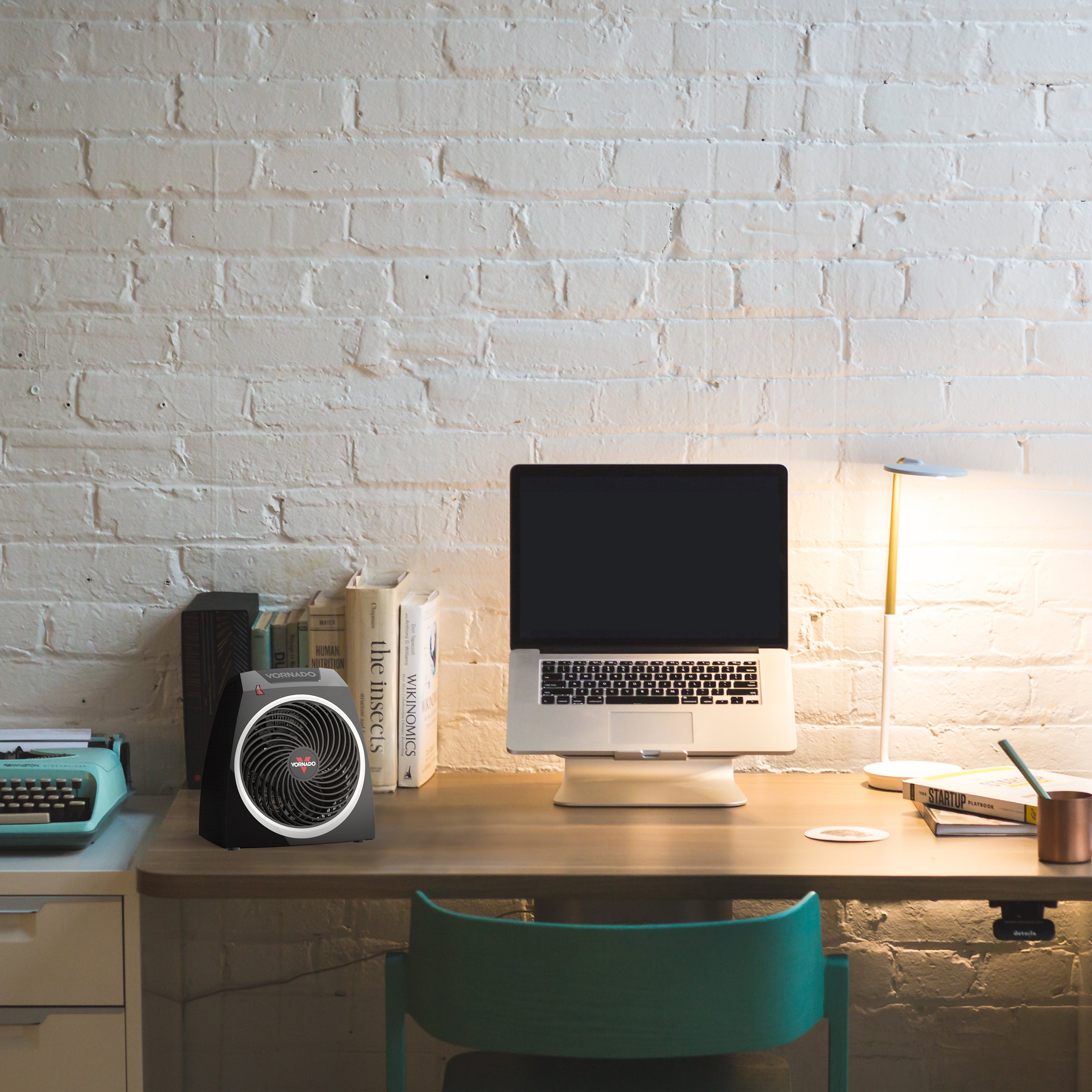 VH5 on a desk in front of books and next to a laptop on a stand with a lamp and concrete wall as a backdrop