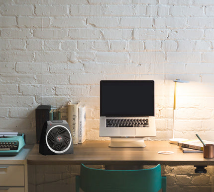 VH5 on a desk in front of books and next to a laptop on a stand with a lamp and concrete wall as a backdrop