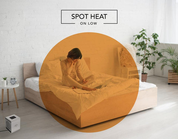 Woman reading on her bed with the VMHi500 heater on the floor. There is an orange circle overlay on her to indicate spot heat on low.