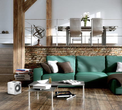 VMHI500 in a living room with a green couch and coffee table, books, and a loft area above the heater