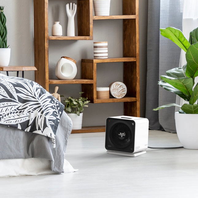 velocity cube 5S on a laminate floor between a bed, plants, and a shelf containing various pottery decor