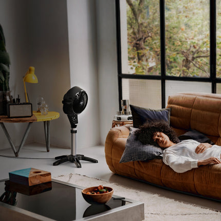 Vornado 6803 OSC pedestal air circulator providing quiet whole-room air circulation while a person rests on a sofa.