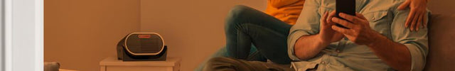 Couple sitting on couch as VC-01 runs on a nearby table. There is a transparent orange overlay to indicate a warm room.