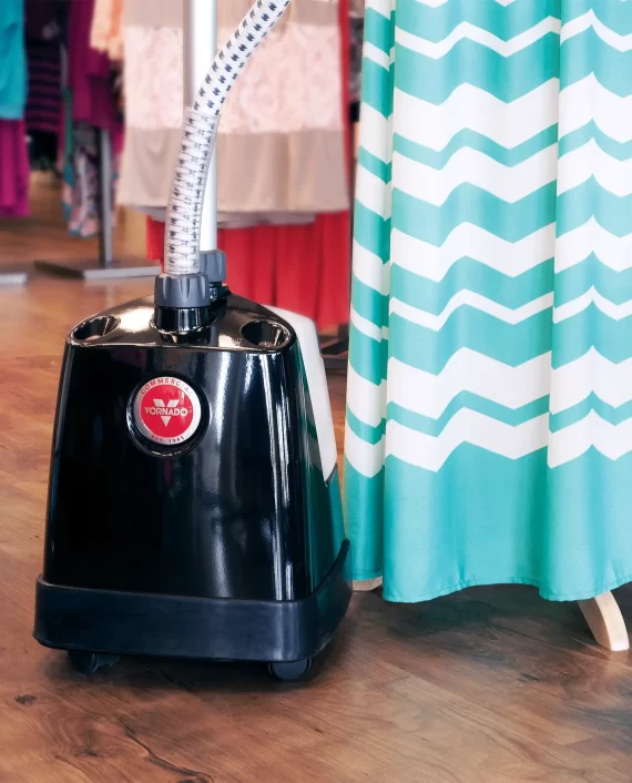 Closeup lifestyle image of Vornado VS 570 tank being used to steam a teal and white dress.