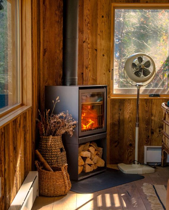 VFAN Sr Pedestal Vintage White next to a wood stove in a rustic cabin